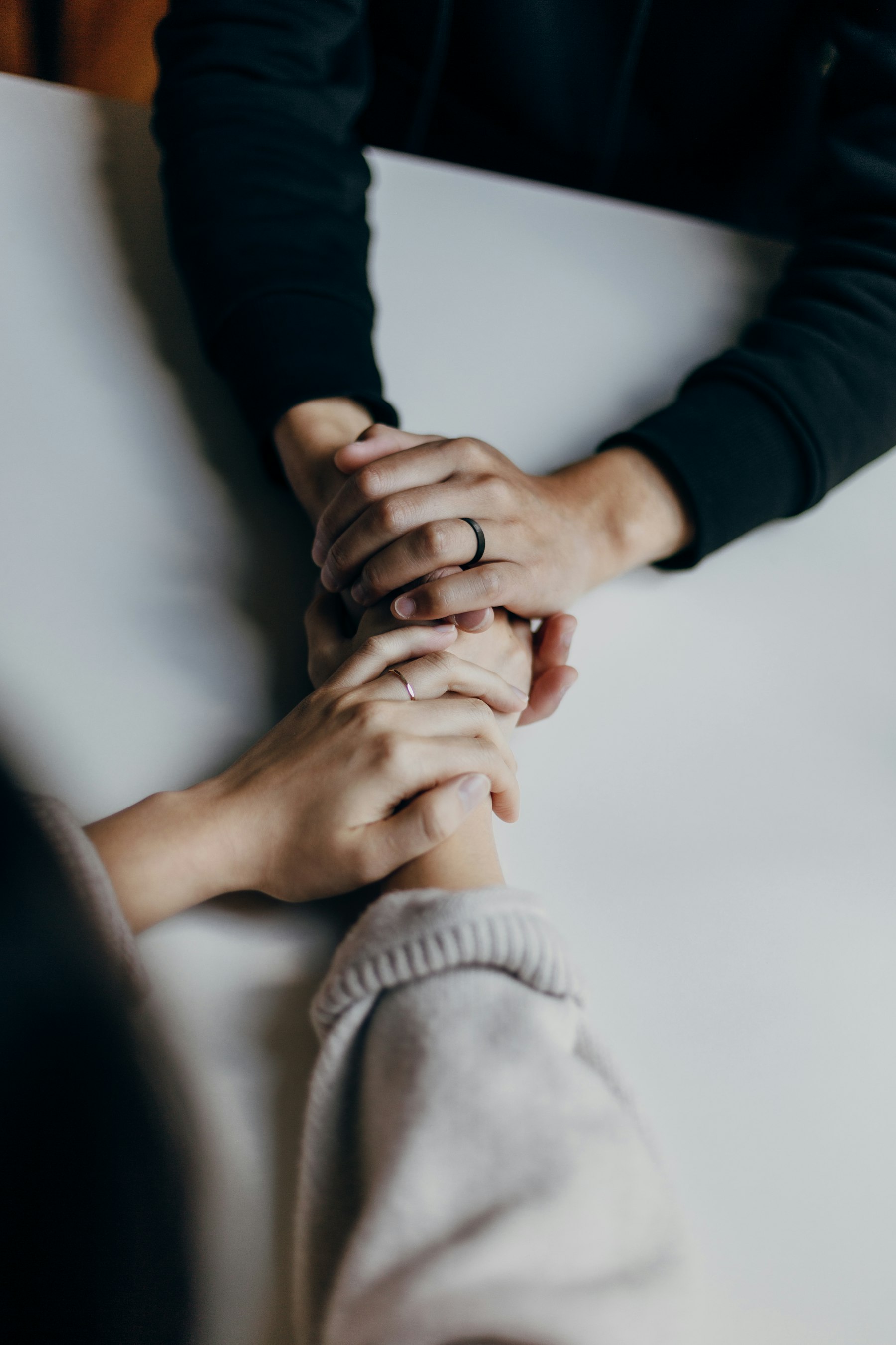 Two people holding hands across a table in support